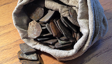 Gamle mynter ligger i en tøypose. Foto: Håkon Roland, Kulturhistorisk museum, Universitetet i Oslo.