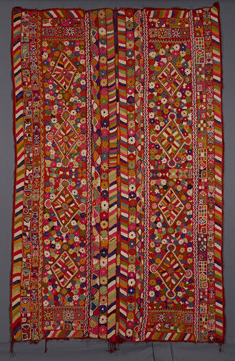 (UEM49200) The blanket has&amp;#160;triple borders down the four edges. The outer vertical borders has the characteristic multi coloured diagonal-lines pattern. In each panel there are four diamonds in a field of flowers and motifs consisting of vegetal and living creatures such as a turtle-like animal (with ears!), a seated figure, insects and also star- like motifs.&amp;#160;