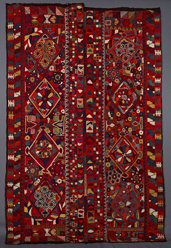 (UEM49210) The blanket has double borders at vertical edges but no characteristic multi coloured diagonal-lines pattern. In the centre of the panels there are four diamonds within which there are flowers and animals surrounding the diamonds a profusion of flowers and animals such as camels and dogs, also insects and other stylised unidentifiable motifs.&amp;#160;