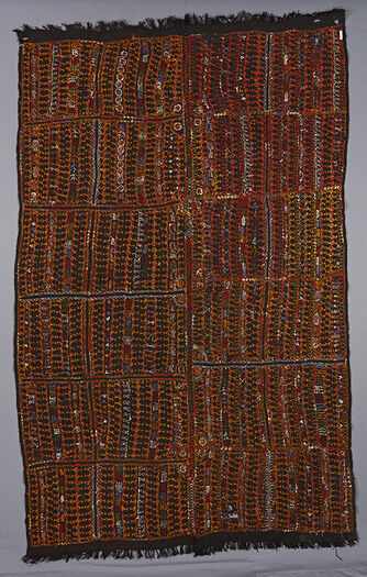 (UEM49211) The background cloth is black, much thinner and not hidden by the embroidered work as in the others in the series.No border but a thin line of embroidery outlines the embroidered section from the edges. Each panel of the blanket is divided into twelve sections giving impression of a grid. There is an over all pattern of repeated stylised motifs in rows. Unidentifiable motifs are possibly sheeves of grass, huts, comb-like motif, timeglass motif also plants and ferns. Spreading over both panels of the blanket/over the middle seam are circles in which there are flowers and other unidentifiable motifs&amp;#160;