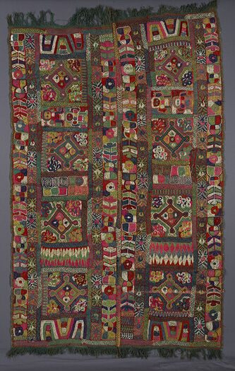(UEM49212) Green background cloth. Double borders at all four verticals of stylised plants and insects. Each vertical panel of the blanket has four diamonds each contained in a square. In the squares and also inside the diamonds are circles&amp;#160;and perhaps&amp;#160;stylised flowers. In between these&amp;#160;four&amp;#160;sections are narrower sections with the following motifs: An unidentifiable motiv, male figures,&quot;whirlpools&quot;, crisscross pattern forming diamonds, and a repetion of the unidentifiable motif.&amp;#160;This blanket is quite different from the others.&amp;#160;