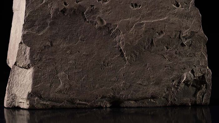 Nærbilde av runer risset inn på en stein.